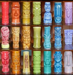many different colored tiki glasses are lined up