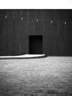 a black and white photo of an open door in the middle of a grass field
