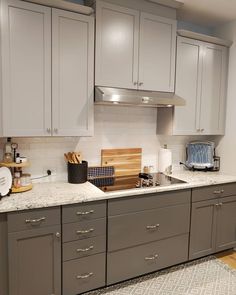 a kitchen with gray cabinets and white counter tops