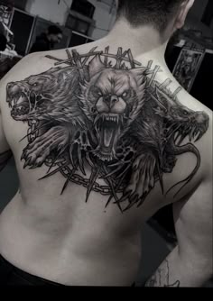 the back of a man's chest with an angry bear and demon tattoo on it