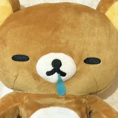 a brown teddy bear with a blue tag on its nose and tongue sticking out from it's mouth