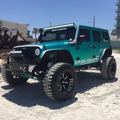 a green jeep parked on top of a sandy beach