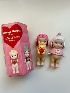 three toy figurines sitting next to each other in front of a pink box