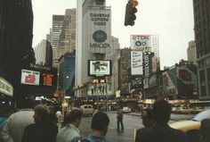 people are standing in the middle of a busy city street with tall buildings and billboards