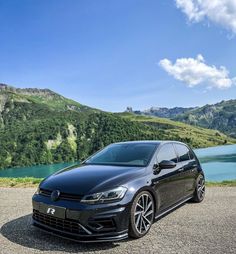 a black car parked on the side of a road next to a body of water