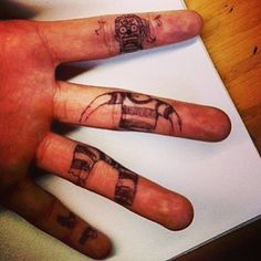 a hand with some tattoos on it that is next to a piece of white paper