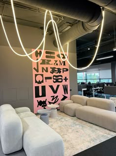 an office lobby with couches, tables and lights hanging from the ceiling above them