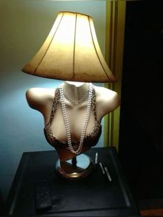 a mannequin with pearls and a lamp on a table next to a remote control