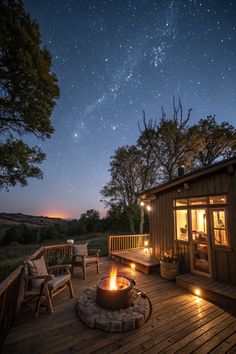 a wooden deck with a fire pit and chairs under the stars in the night sky