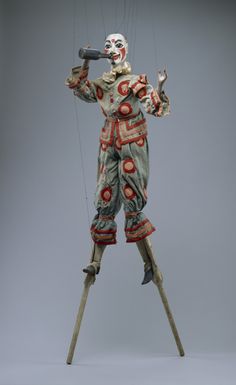 a statue of a clown holding two strings in one hand and an object in the other