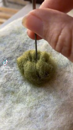 someone is needleing something on top of a piece of felt
