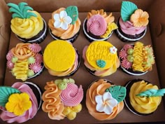 a box filled with lots of colorful cupcakes on top of each other in different flavors
