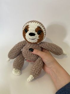 a hand holding a small stuffed slotty bear