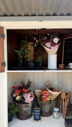 flowers are sitting in buckets on the shelves