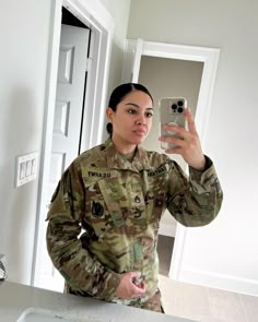 a woman in uniform taking a selfie with her cell phone while standing in front of a sink