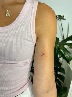 a woman wearing a pink tank top and white shorts with a small tattoo on her arm