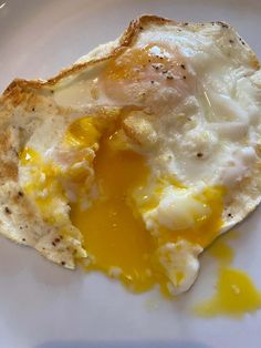an egg and some sort of bread on a white plate with yellow liquid coming out of it
