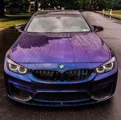 a purple bmw is parked on the side of the road in front of some trees