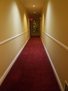 an empty hallway with red carpet and white trim