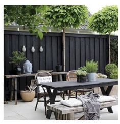 an outdoor table and bench with potted plants