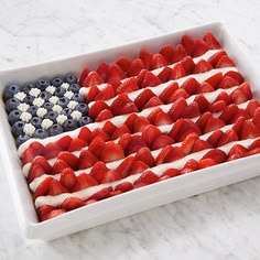an american flag made out of strawberries in a white dish on a marble counter