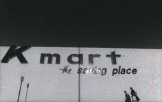 two people walking in front of a building that has a large sign on the side