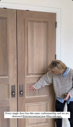 a woman standing in front of a wooden door with her hand on the side of it
