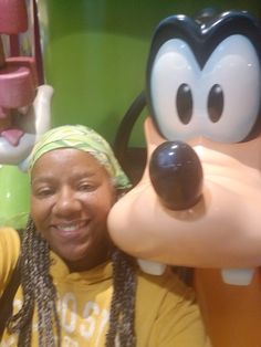 a woman poses with goofy and pluto characters