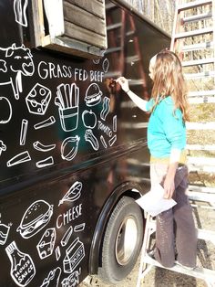 a woman writing on the side of a food truck