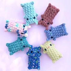 small crocheted animals are arranged in a circle on a white surface, including one blue and one green