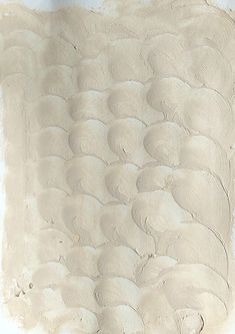 a person standing in front of a wall covered in sand and mud with a surfboard on it's side