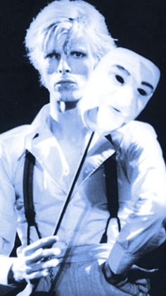 two people with masks on their faces and one person holding something in his hand while the other is wearing a white shirt