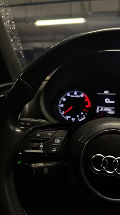 an audi car dashboard with the gauges lit up and water droplets on the steering wheel