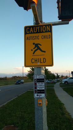 a yellow caution sign on a pole next to a street