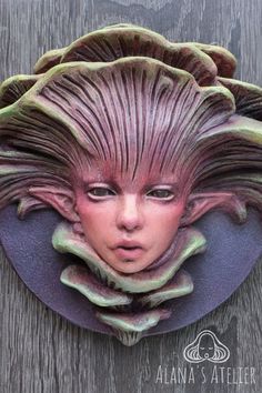a woman's face is made out of clay and sits on top of a purple plate