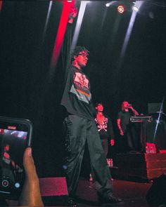 a man standing on top of a stage holding a cell phone