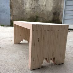 a wooden bench sitting on top of a cement floor next to a building with a garage door in the background