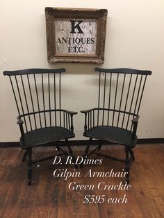 two black chairs sitting next to each other in front of a painting on the wall