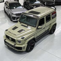 several cars are parked in a showroom with white flooring and black rims