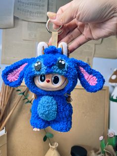 a blue stuffed animal keychain being held by a person's hand,