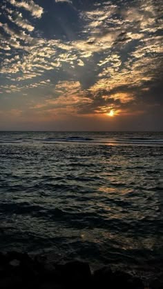 the sun is setting over the ocean with some clouds in the sky and water below