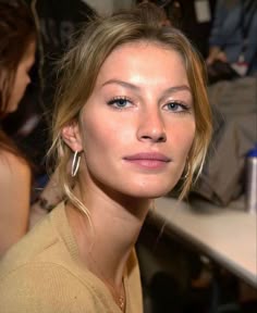 a woman with blonde hair and blue eyes wearing large hoop earrings at a fashion show