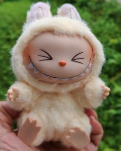a hand holding a small doll in the shape of a bunny