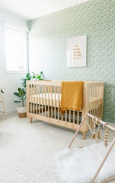 a baby's room with a crib, rocking chair and potted plant