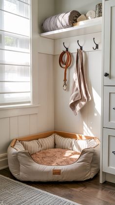 a dog bed in the corner of a room with two coats hanging from hooks on it