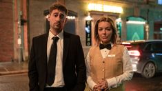 a man and woman standing on the street at night