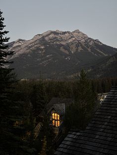 the mountains are covered in snow and there is a small cabin at the bottom of the mountain