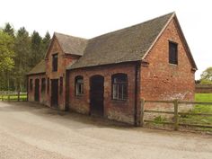 an old red brick building sitting on the side of a road next to a forest