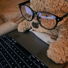 a teddy bear wearing glasses sitting in front of a laptop