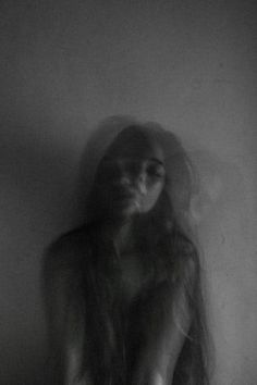 a woman with long hair standing in front of a wall